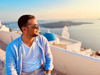 a man is sitting on a ledge overlooking the ocean